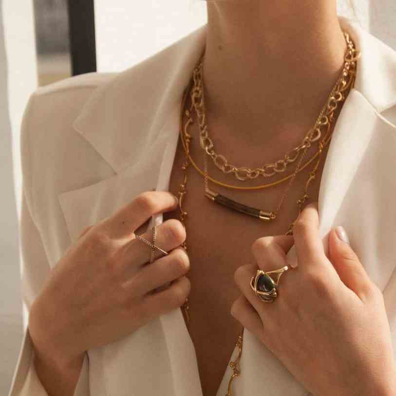 Quanto tempo dura uma joia folheada a ouro? - Folheada 3 Mulher de blazer branco usando várias joias douradas