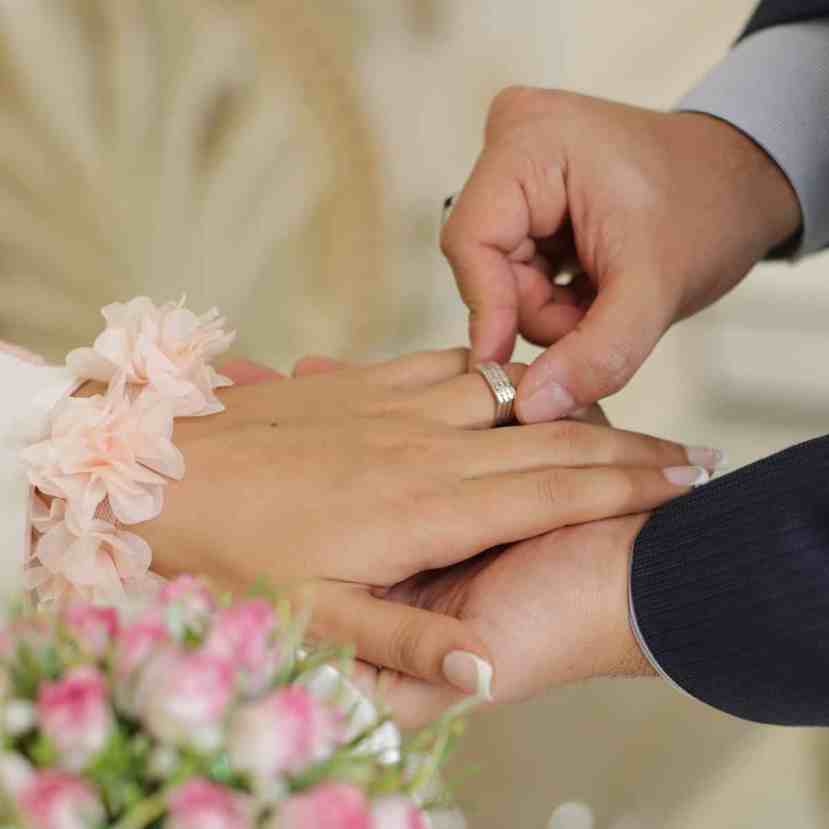 Homem colocando aliança na mão da noiva