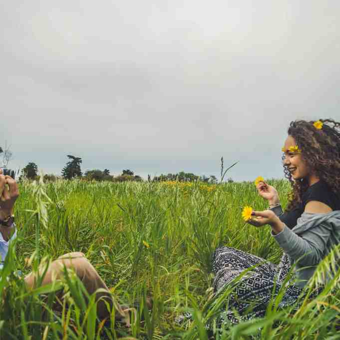 Como melhorar meu relacionamento? 08 Atitudes Simples - Como melhorar relacionamento 2 Homem tirando foto da namorada sentada na grama com flores