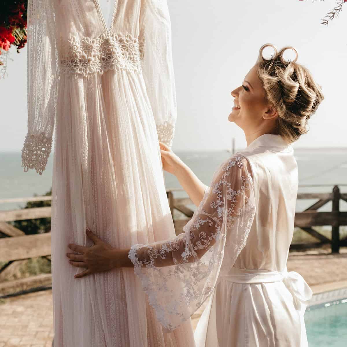 Noiva olhando para seu vestido de casamento enquanto está se arrumando