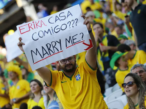 Homem com camisa do brasil segurando placa com pedido de casamento