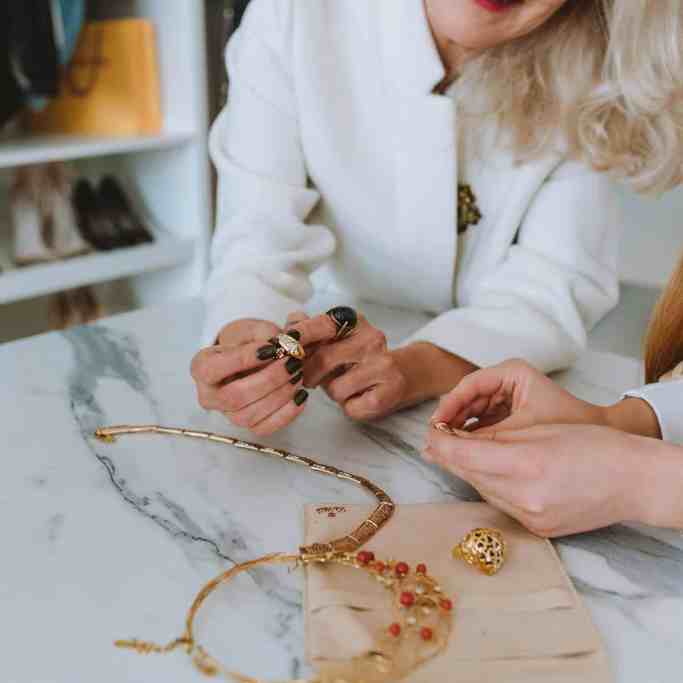 Aliança de Casamento: Tudo o que o você precisa saber para comprar a sua Online - Comprar joia loja fisica Moça escolhendo joias junto a atendente