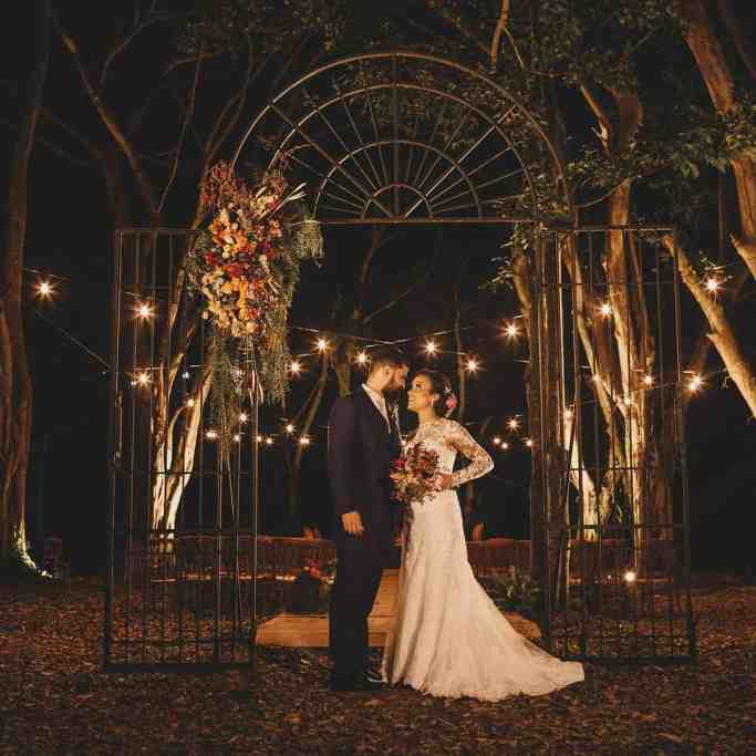 Decoração de Casamento: Guia Completo para Encantar - Iluminacao casamento 1 Casal de noivados posando ao ar livre a noite com luzes iluminando o local