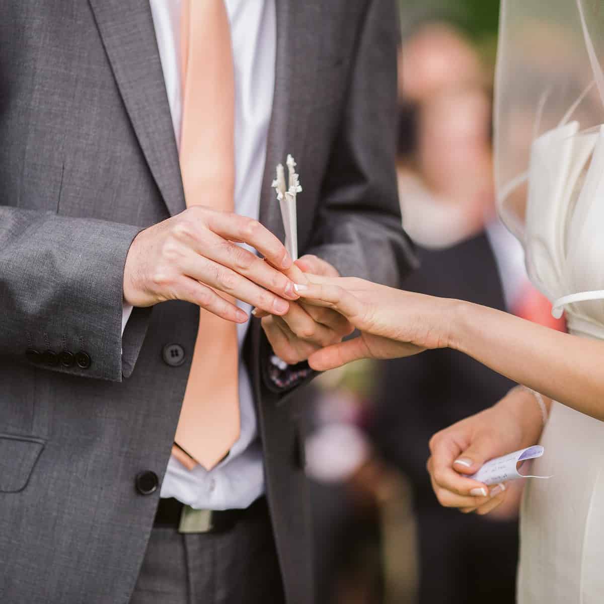 Noivo colocando aliança no dedo da noiva