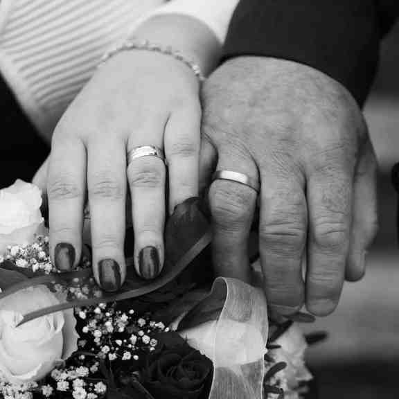Casal usando aliança de casamento, a imagem está em preto e branco