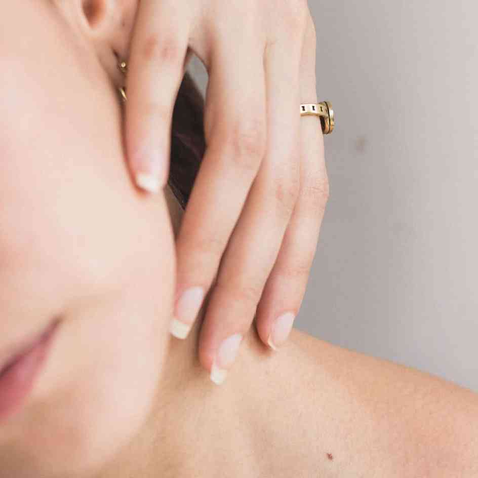 Mulher com a mão no pescoço usando anel - alergia à bijuterias e semijoias: o que fazer?