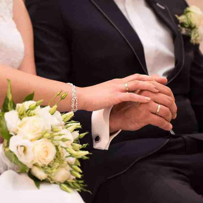 Noivos com mãos se tocando durante o casamento