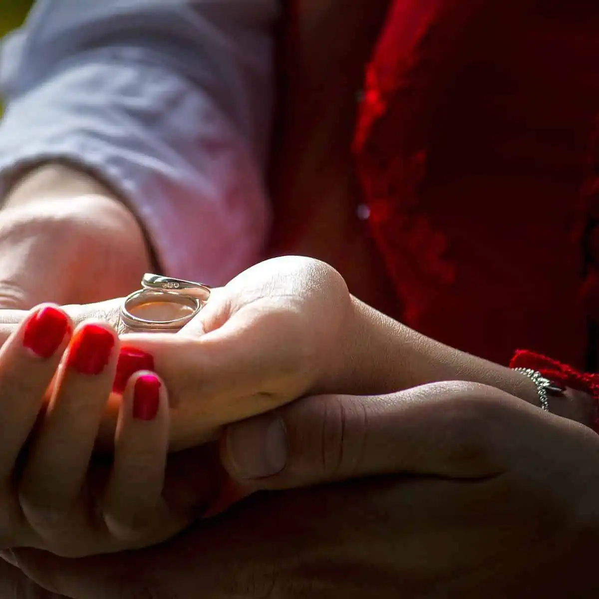 Casal segurando seu par de alianças na mão