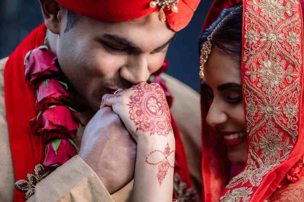 Noivos indianos, o noivo está beijando a mão da noiva