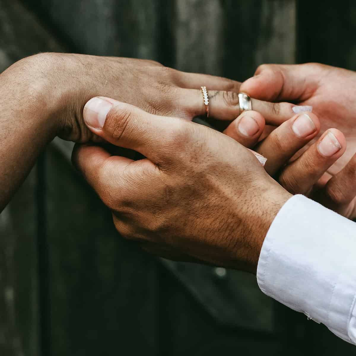 Homem colocando aliança no dedo da noiva