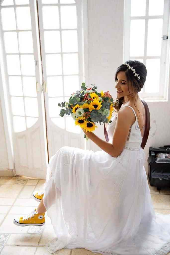 Noiva de tênis amarelo sentada segurando buquê