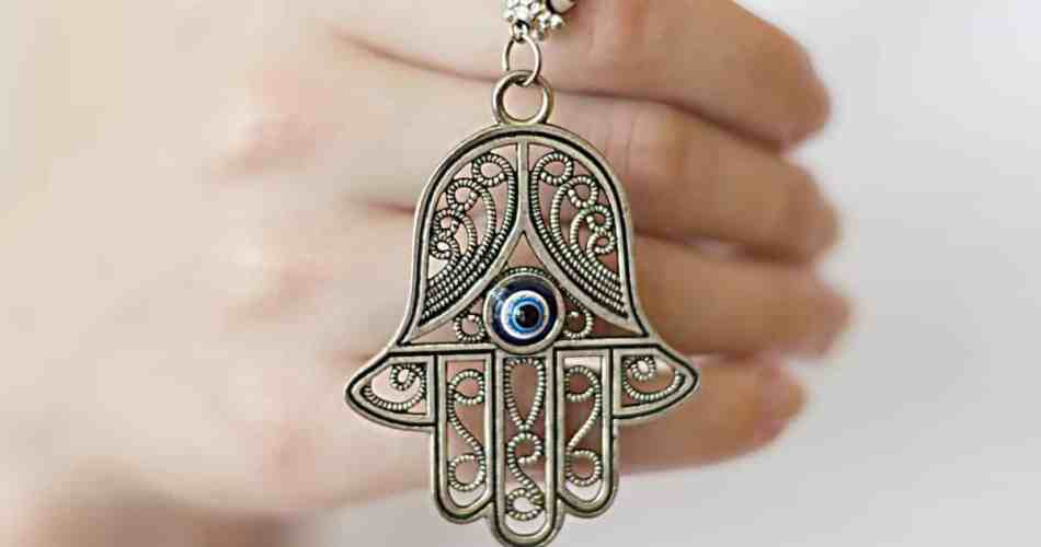 Mulher segurando pingente de hamsa e olho grego
