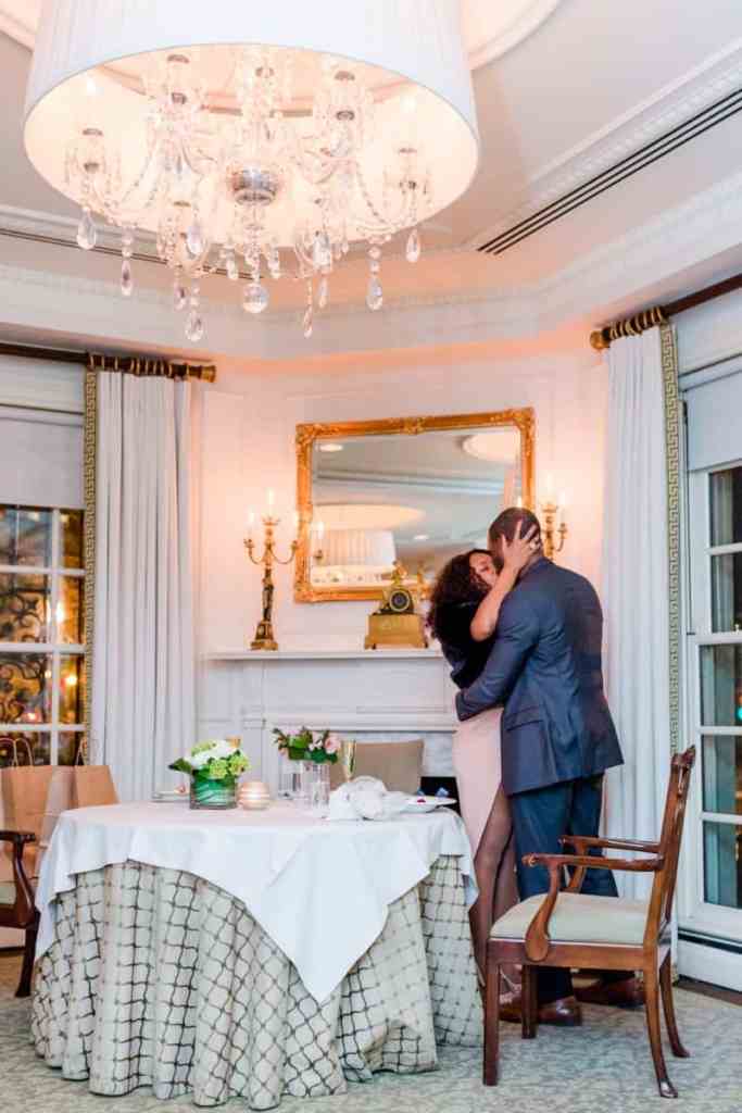 Casal em pé se beijando ao lado de uma mesa - como fazer o pedido de casamento durante o jantar?
