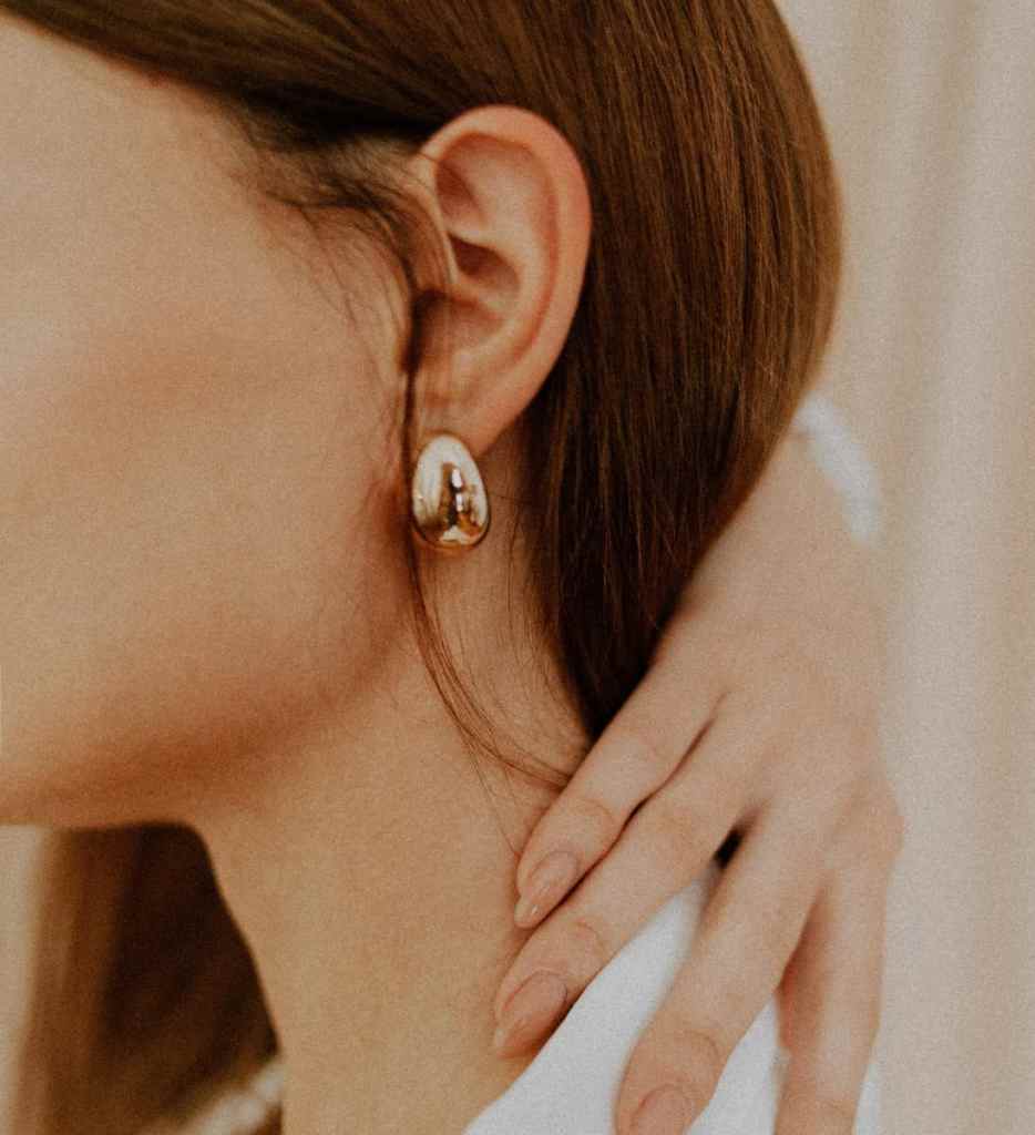 Mulher usando brinco grande oval