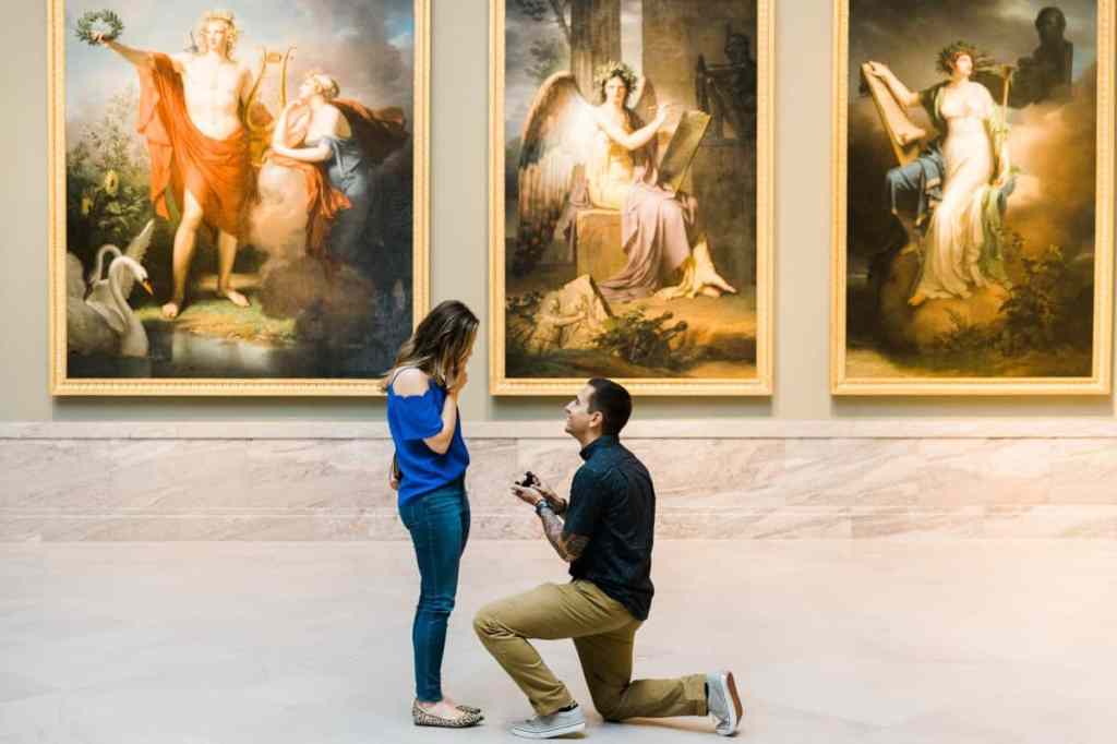 Homem ajoelhado fazendo pedido de casamento no museu