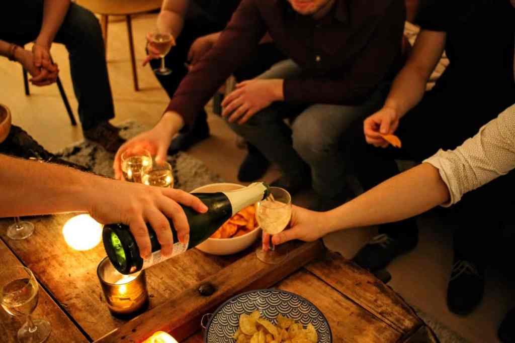 Pessoas sentadas na mesa e uma colocando champagne no copo de uma pessoa
