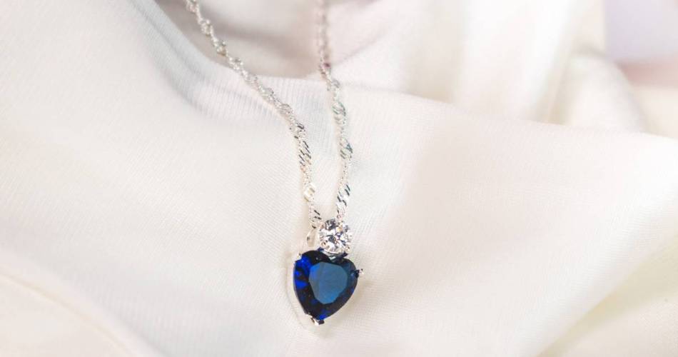 Colar com pedra azul em formato de coração sob fundo branco