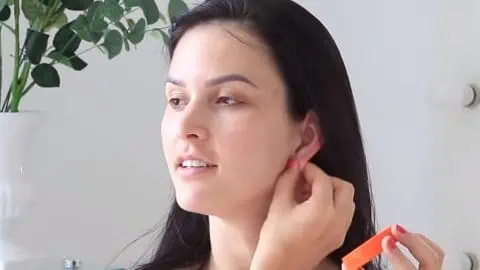 Mulher com a mão na orelha inflamada