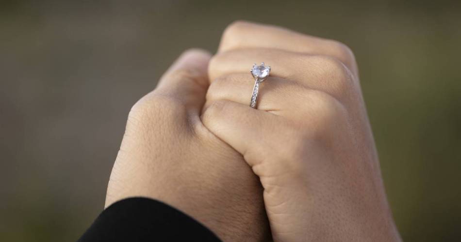 Homem segurando mão da noiva que está com anel de noivado