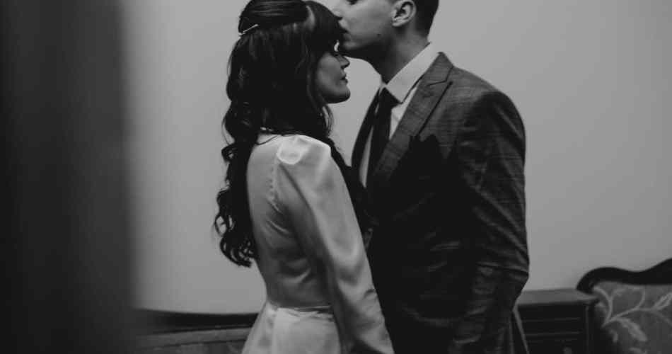Noivo beijando a testa da noiva, a fotografia está em preto e branco