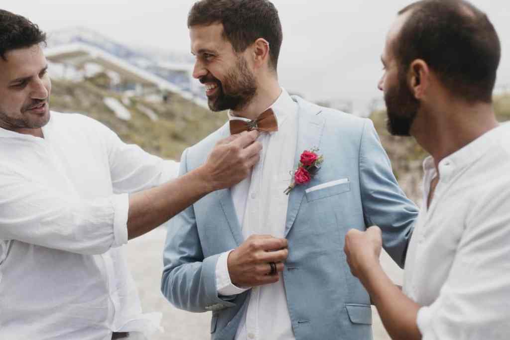 Padrinhos de casamento do noivo arrumando a gravata dele