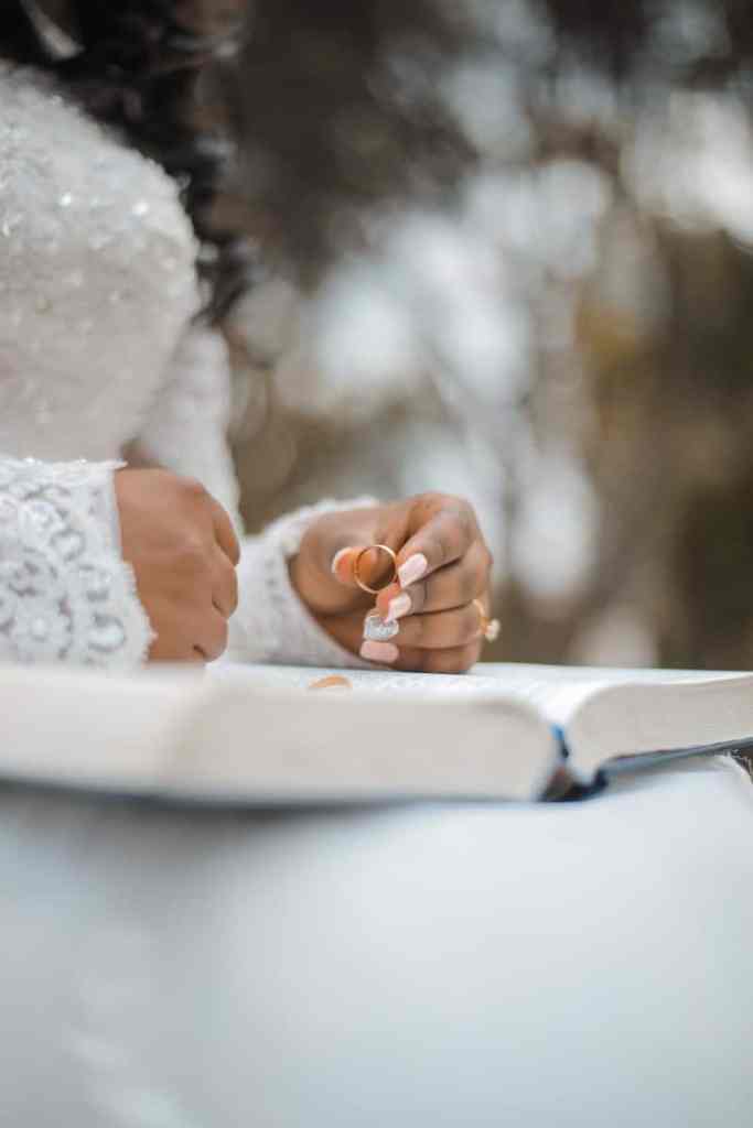 Noiva sentada segurando aliança em cima da bíblia