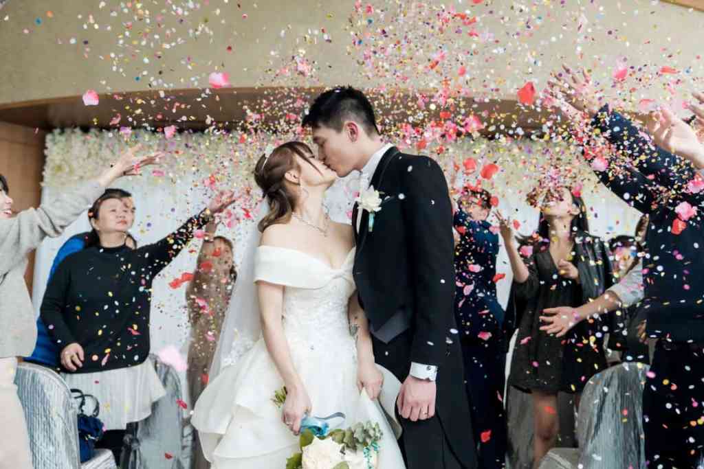 Noivos se beijando no casamento, os convidados estão jogando pétalas de flores