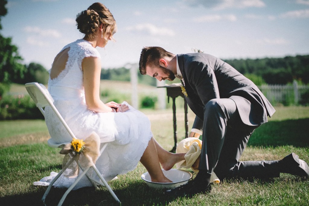 Noivo lavando o pé da noiva, eles estão em uma cerimônia ao ar livre
