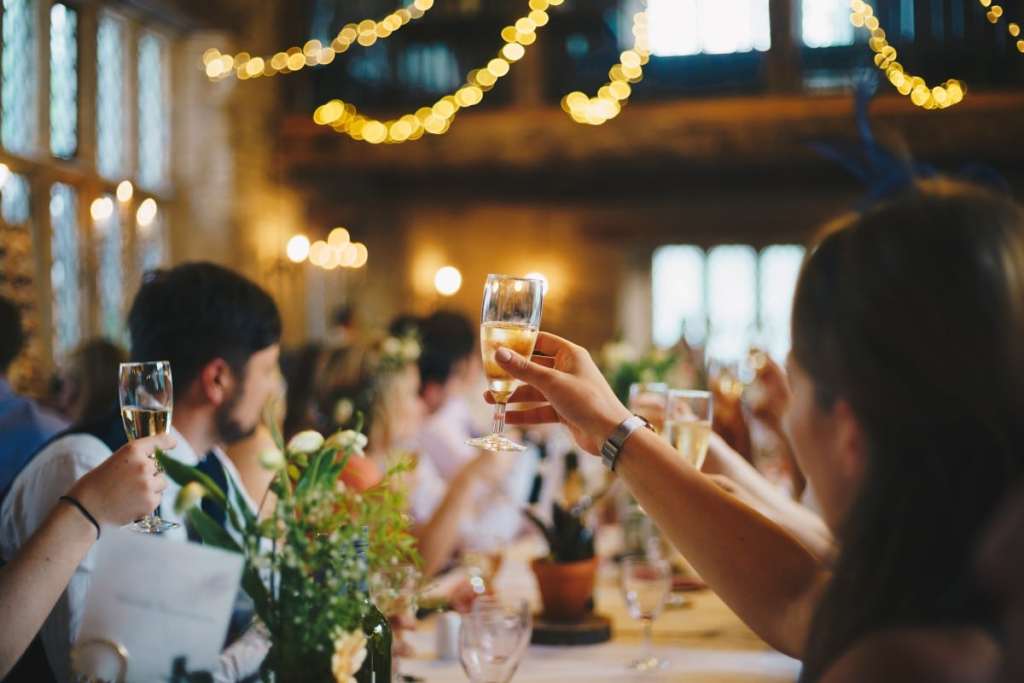 Pessoas em casamento levantando suas taças - como ser a madrinha perfeita?