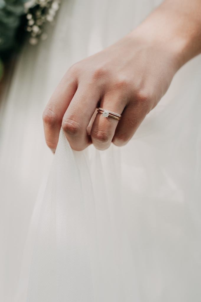 Mão de noiva com anel de noiva e meia aliança