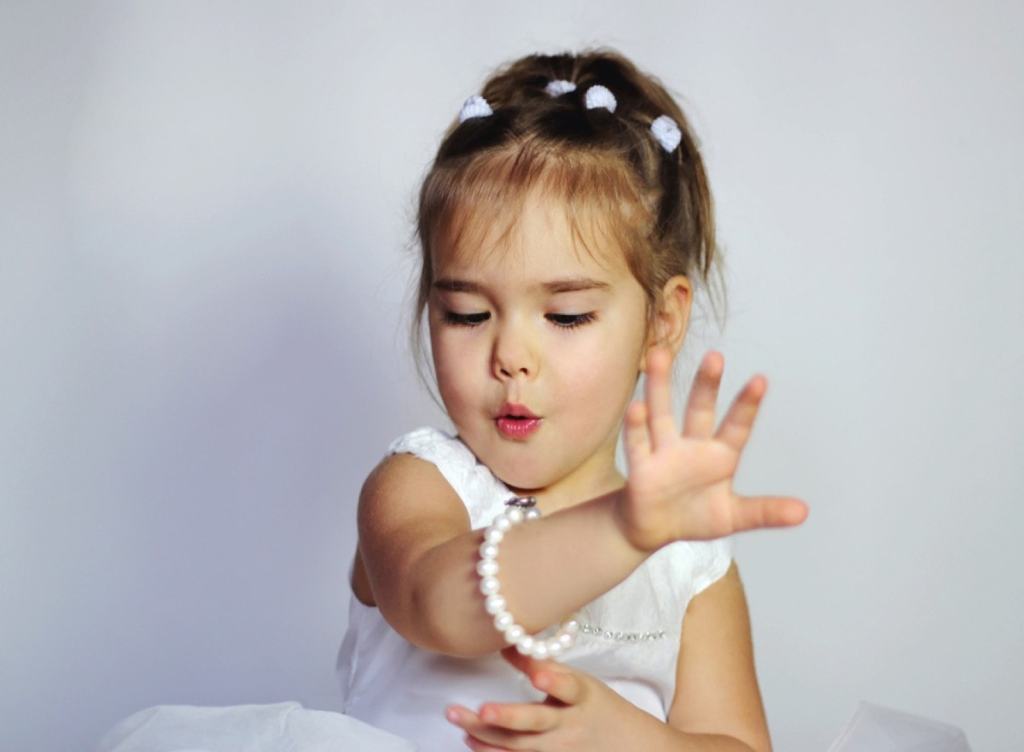 Garota usando pulseira de pérolas - quais os principais cuidados com as joias infantis?