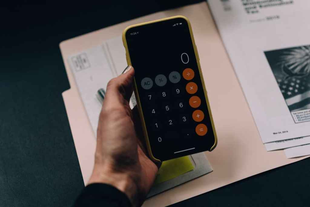Pessoa com celular na mão e a calculadora aberta
