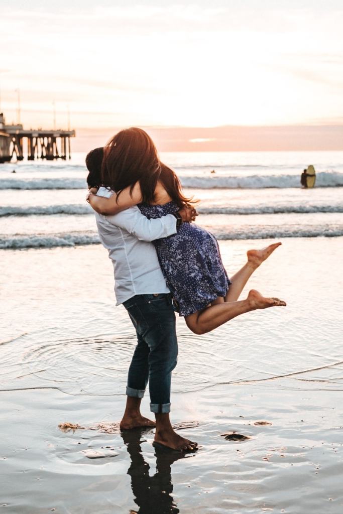 Homem e mulher abraçados girando na praia
