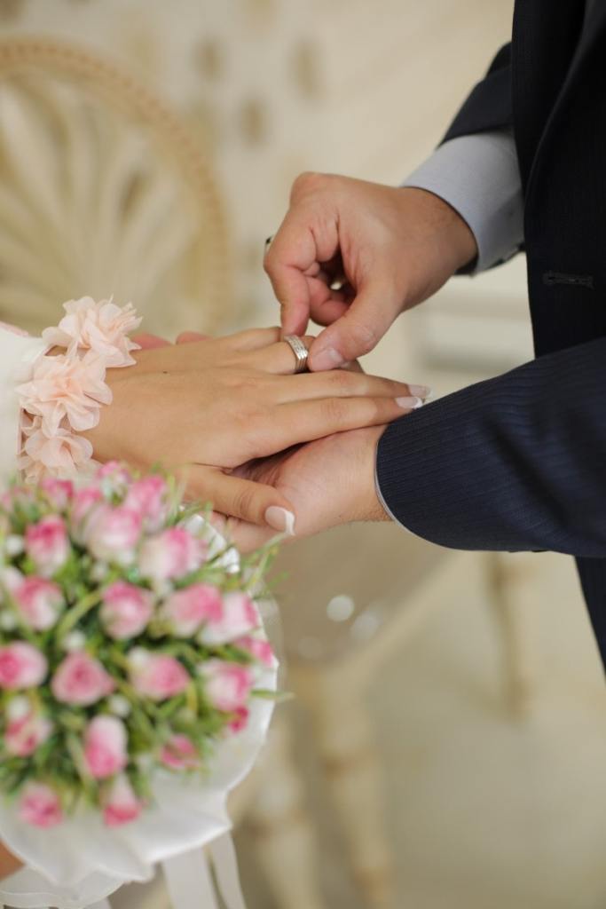 Homem colocando aliança em dedo de sua noiva