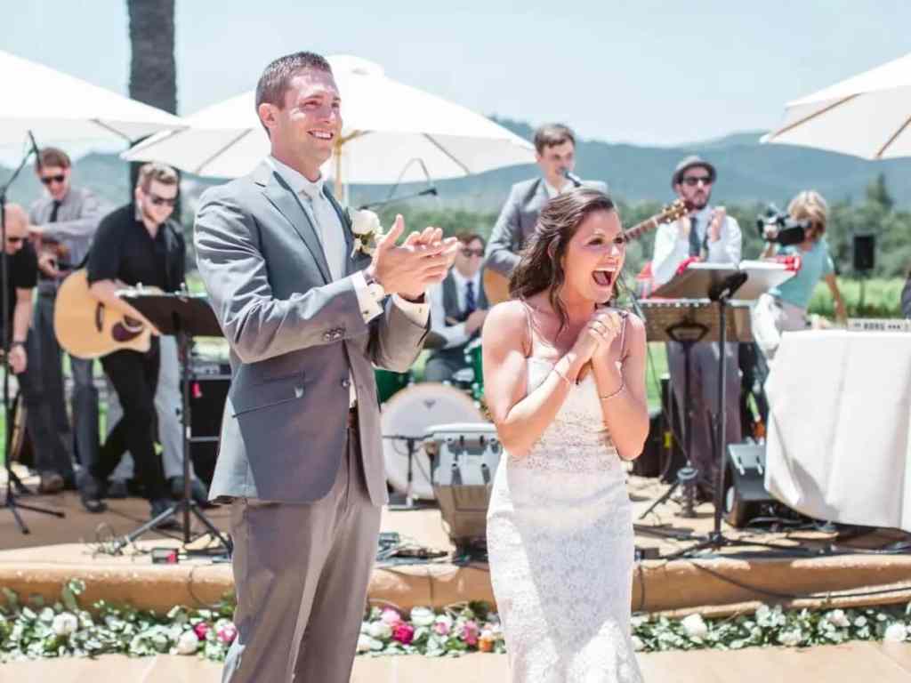 Noiva e noivo animados batendo palma enquanto a banda toca no casamento