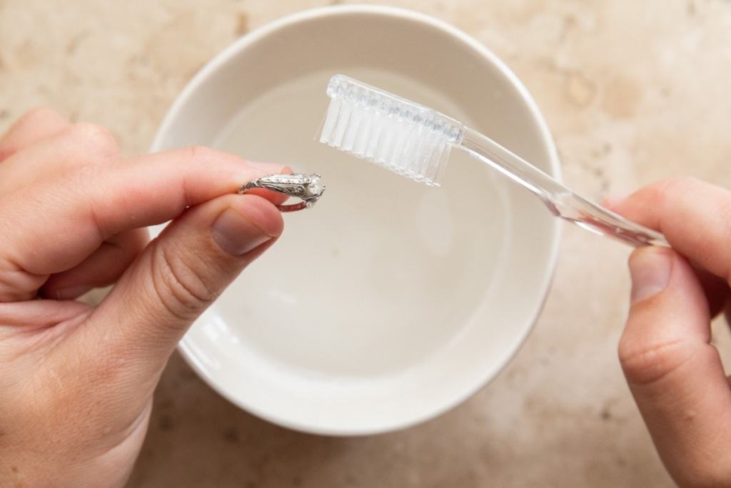 Mulher limpando com escova de dente um anel de prata - como escolher o anel perfeito?