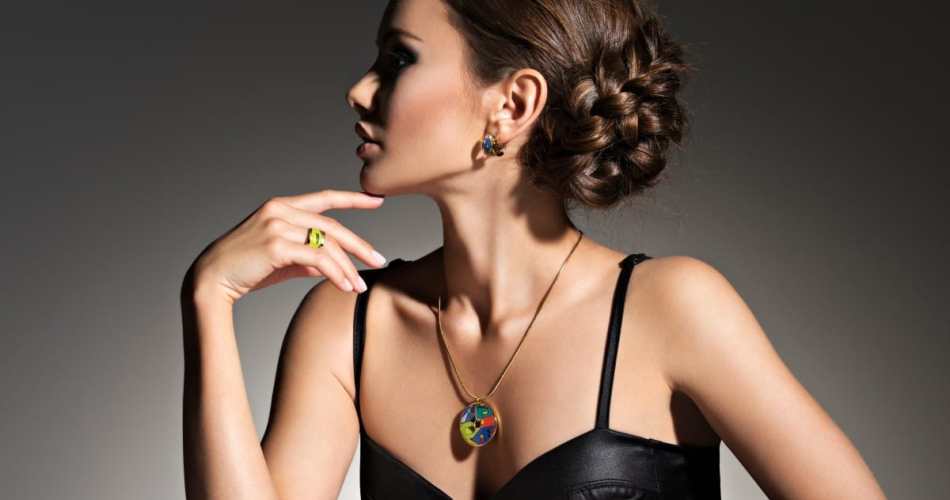 Mulher de perfil, ela está virada para a esquerda. Usa coque, regata preta e joias.