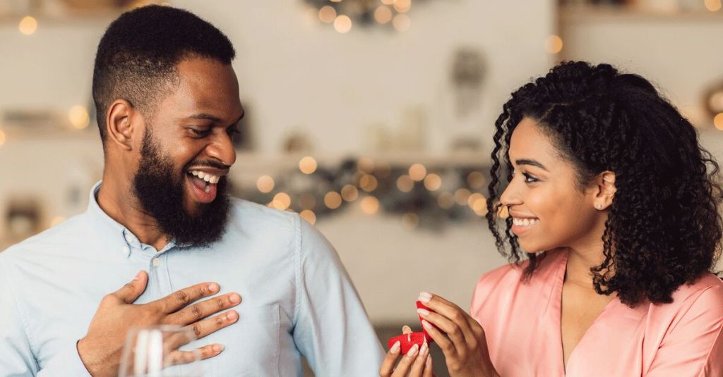 Mulher pede namorado em casamento, no fundo estão luzes pisca pisca