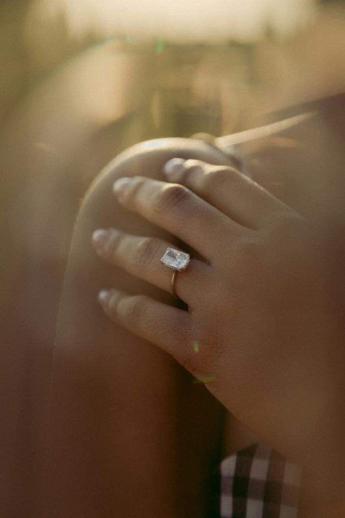 Mulher apoiou a mão no ombro, ela está usando um anel de noivado quadrado - lab grown diamonds: o que é o diamante de laboratório?