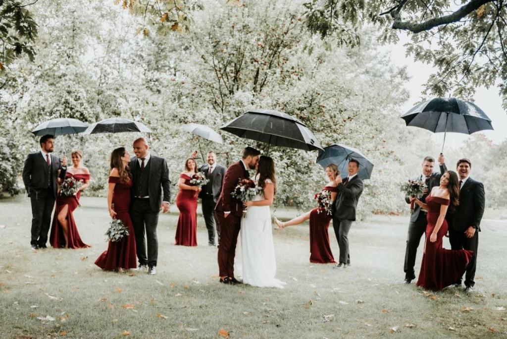 Convidados em par e noivos debaixo de guarda-chuvas