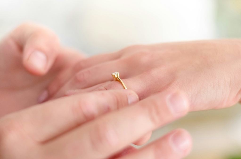 Homem colocando anel de noivado de ouro em mão da noiva