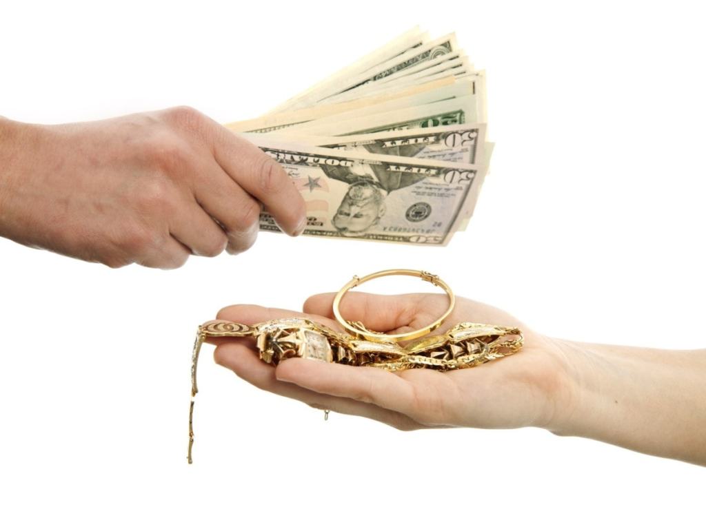 Um braço esticado com joias e outro braço esticado entregando dinheiro. Demonstra a troca que aconteceria numa penhora de joias.