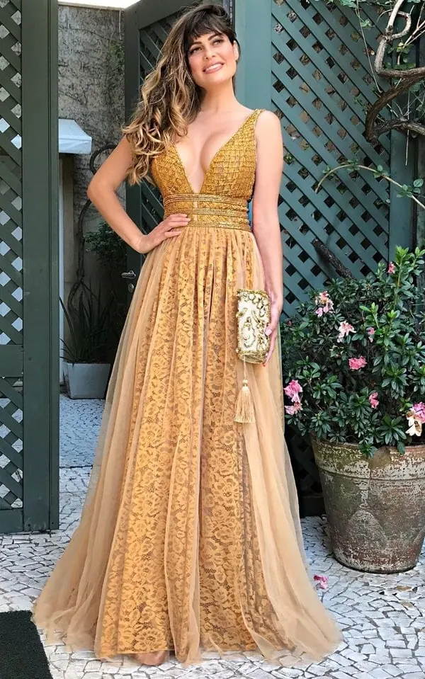 Mulher usando vestido longo dourado com decore em v, e estampa de flores bordadas - 10 dicas para escolher o vestido de formatura
