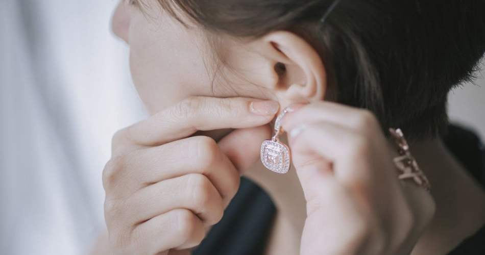 Mulher colocando brinco na orelha