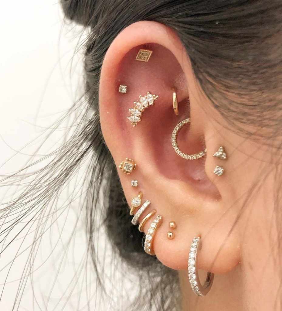 Foto de orelha com vários piercings.